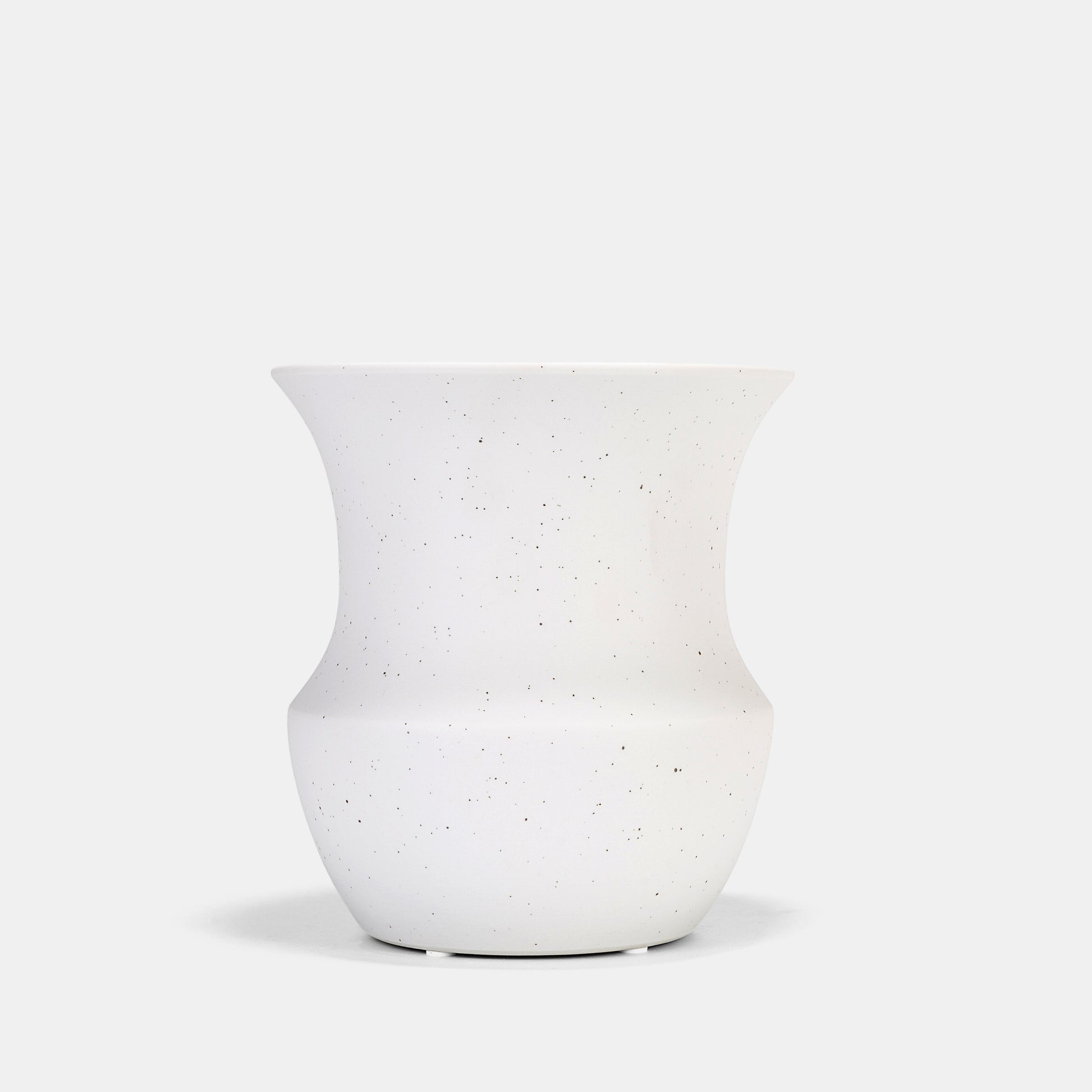 This ceramic vase’s matte white surface transitions from functional vessel to sculptural decor. Its speckled texture complements flowers on vase arrangements or dried grasses, while the neutral palette harmonizes with bud vases in eclectic tablescapes. 